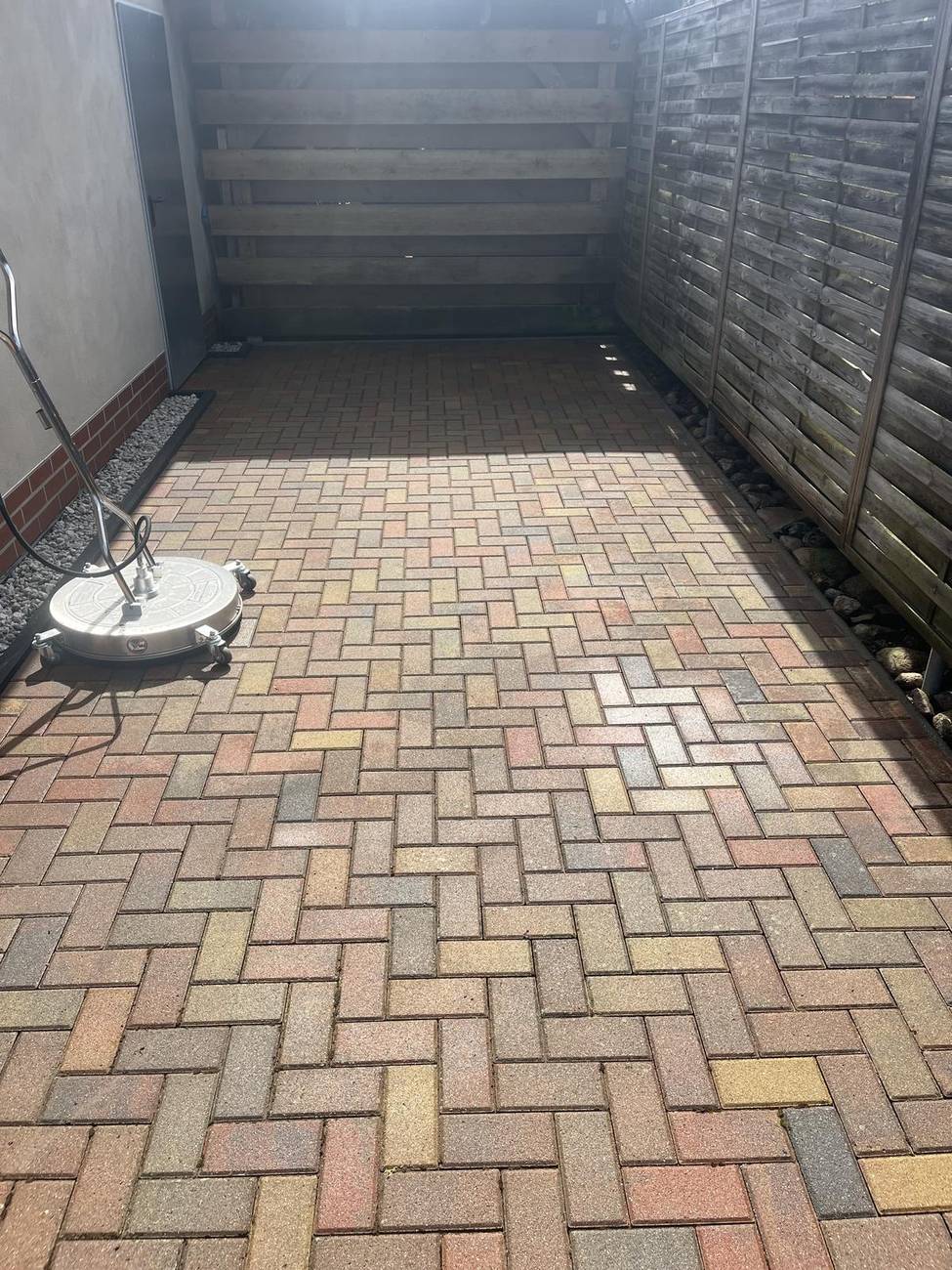 Frisch gereinigte Pflasterfläche mit Flächenreiniger im Hintergrund